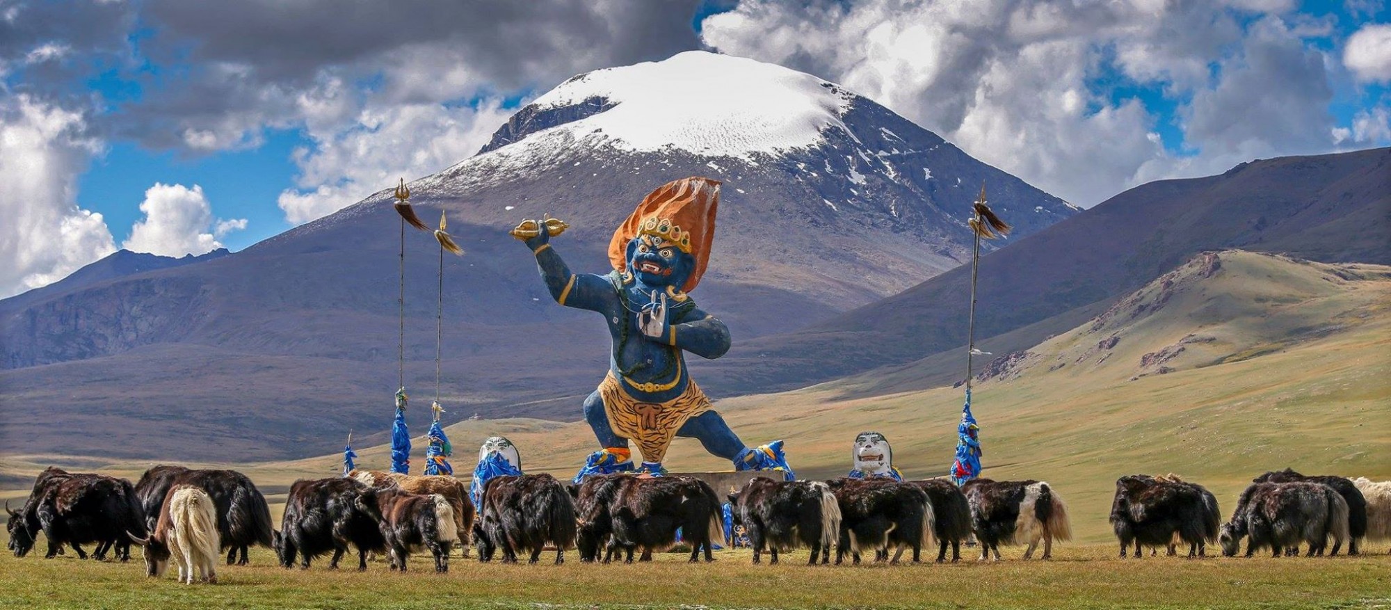 Landscape of Zavkhan Province, Mongolia, with a mountainside monument and yak herd on the grassland
